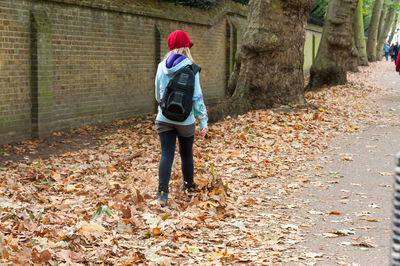 Rear view of man walking on street during autumn