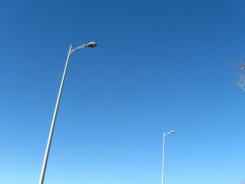 Low angle view of street lights against clear blue sky