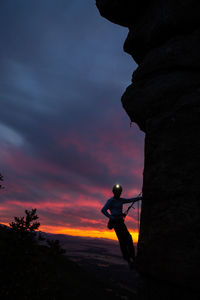 Side view of sportive male alpinist ascending on cliff in mountain terrain in cloudy day