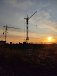 Crane on field against sky during sunset