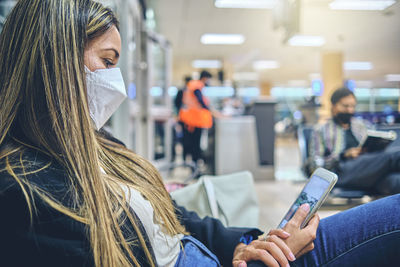 Beautiful young woman looking out window at flying airplane while waiting boarding on aircraft