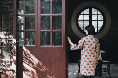 Rear view of woman standing by window