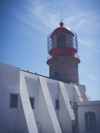 Low angle view of lighthouse by building against sky