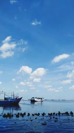 Boats moored in sea against blue sky