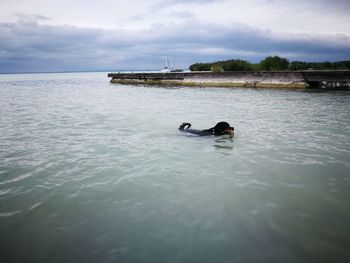 Man swimming in sea against sky