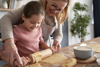 Grandma and granddaughter rolling dough