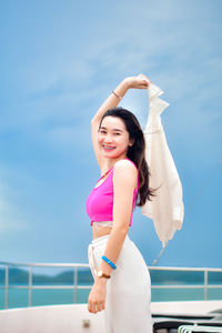 Portrait of young woman standing against sky