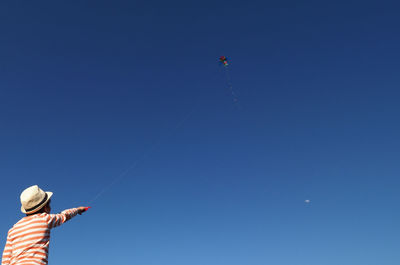 Low angle view of man flying kite against sky