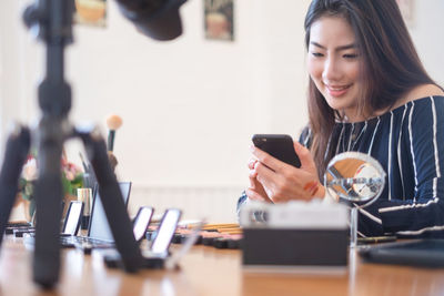 Young woman using phone while sitting on table