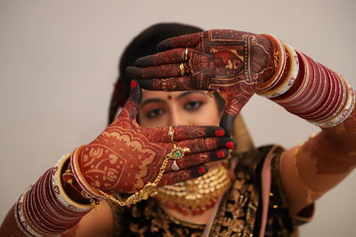 Close-up portrait of bride showing henna tattoo against white background