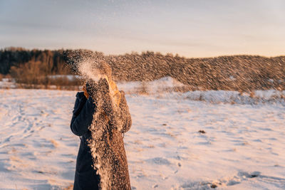 An unidentified woman throws snow in a snow-covered field