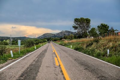 Road by trees against sky