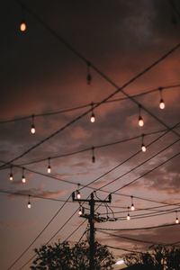 Low angle view of illuminated lights against sky at sunset