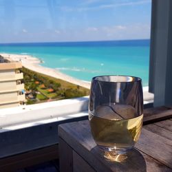 Close-up of drink on table by sea against sky