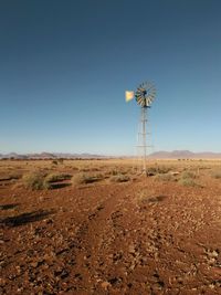 Wind turbines on field against clear blue sky