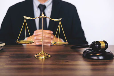 Midsection of judge with gavel and weight scale desk