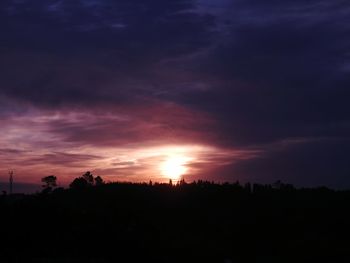 Silhouette of trees against dramatic sky