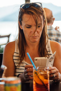 Woman using mobile phone while having drink in restaurant