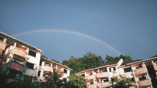 Low angle view of rainbow over buildings against sky