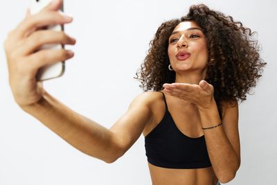 Portrait of smiling young woman gesturing against white background