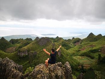 Full length of man sitting on rock against sky