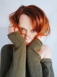 Close-up portrait of mid adult woman with hands on chin standing against wall at home