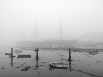 Boats moored in harbor during foggy weather