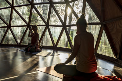 Woman practicing yoga with female fitness instructor in health retreat