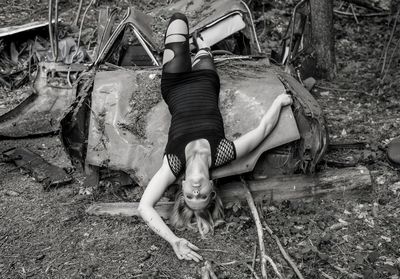 High angle view of mid adult woman lying on damaged car