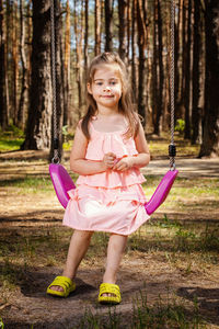 Portrait of girl sitting on swing in playground