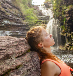 Side view of woman looking at waterfall