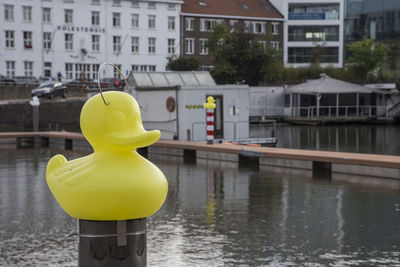 Yellow by railing against river and buildings in city