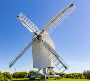 Low angle view of windmill on field against sky