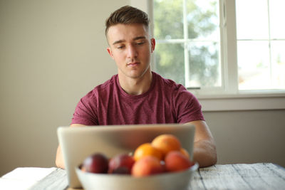 Young man looking away while sitting on table