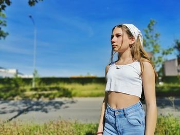 Young woman standing against sky