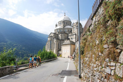 Rear view of people walking amidst buildings against sky