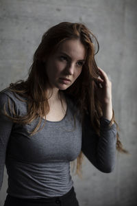 Beautiful young woman looking away while standing against wall