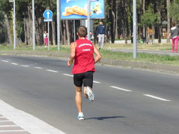 Rear view of woman running on road