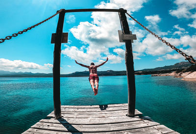 Shirtless man diving in sea against blue sky