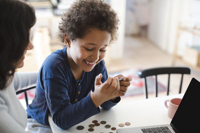 Happy boy looking at credit card while sitting with mother at home