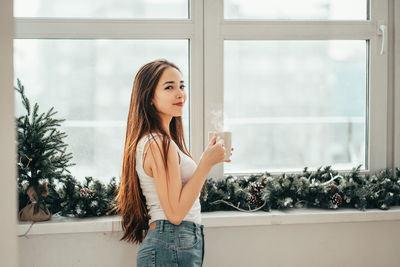 Woman standing by window at home