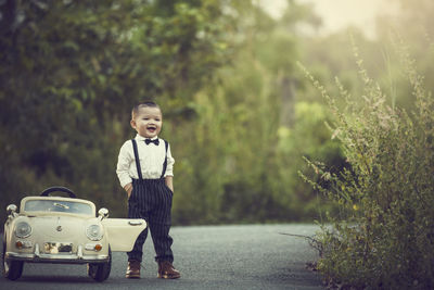 Portrait of boy standing by car