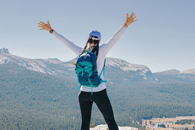 Woman hiker standing with her hands raised on the top of the mountains. success concept.