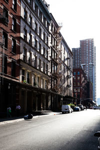 Cars on city street by buildings against sky