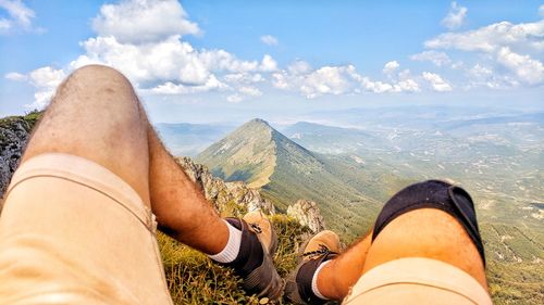 Low section of man against mountains against sky