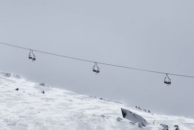 Low angle view of overhead cable cars against snowcapped mountain