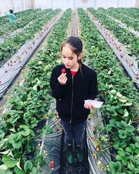 Young woman looking away while standing on plants