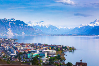 City by lake and mountains against sky