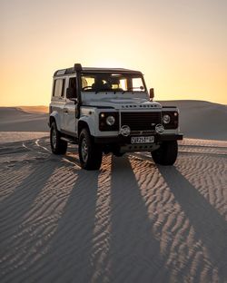 Vintage car on beach against sky during sunset