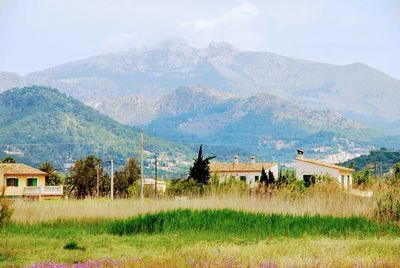 Houses on field by mountains against sky